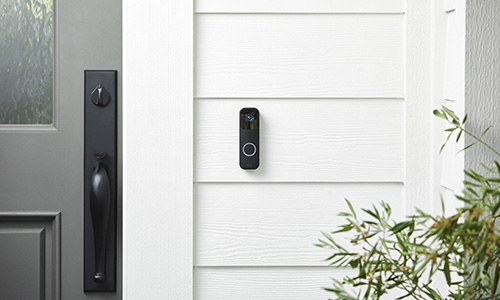 The Blink Video Doorbell mounted by the front door of a nicely painted house.