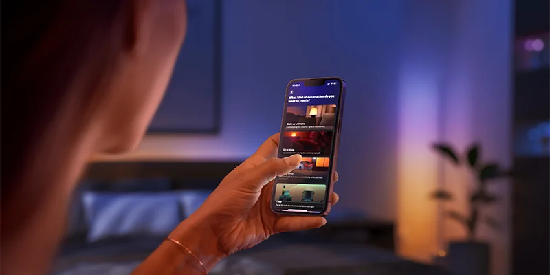 A woman using the Philips Hue app on her smartphone.